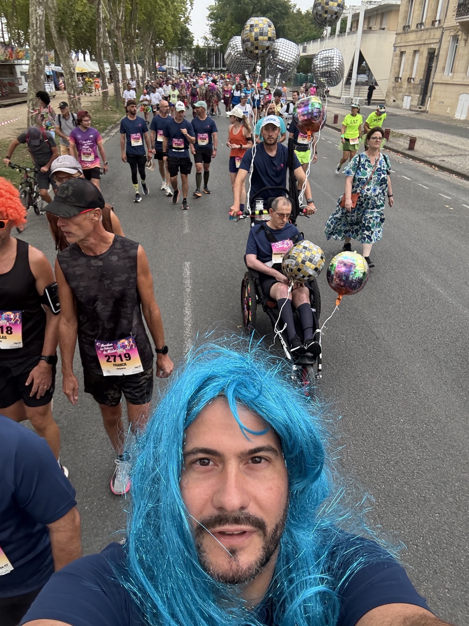 Xavier Lacombe en perruque bleue, avec derrière lui Stéphane Craviotto dans son fauteuil et l'équipe de Pontet-Canet parmi les coureurs